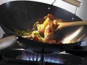 Frying strips of meat & vegetables in a wok over a gas flame