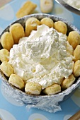 Whipped cream in a cake tin lined with sponge fingers