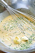 Whisked eggs with whisk in a metal bowl