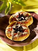 Two mini-pizzas topped with anchovies and olives