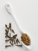 Whole and ground cloves on a porcelain spoon