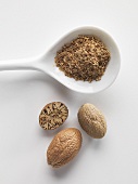 Nutmegs, whole, half and grated on a porcelain spoon
