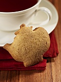Teapot-shaped gingerbread biscuit with a cup of tea