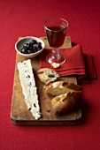 Mit Ziegenkäse gefüllter Brie, Oliven, Baguette und Wein