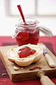 Apple and cranberry jelly in a jar & on half a bread roll