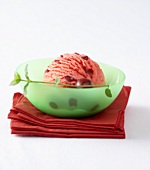 Scoop of cherry ice cream in a glass dish on paper napkins
