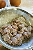 Floured cubes of beef in a bowl