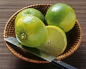 Limes, two whole and one halved in a small basket