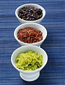 Red, green and black rice in small bowls