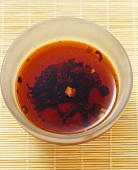 Chilli oil in a small glass dish on a bamboo mat