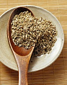 Cumin seeds in a small dish with wooden spoon