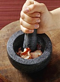 Crushing ingredients for curry paste in a stone mortar