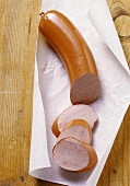 Fleischwurst sausage, partly sliced on paper