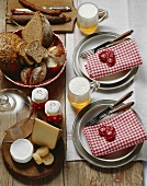 Table laid for hearty snack of cheese, bread, sausage & beer