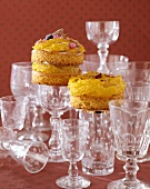 Three orange cakes on glasses, surrounded by glasses
