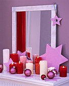 Sterne, Weihnachtskugeln und Kerzen vor einem Spiegel