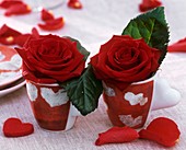 Rote Rosen in zwei Espressotassen mit Herzen