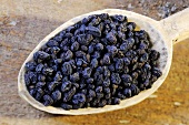 Dried Chinese privet berries on a wooden spoon