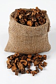Pieces of dried gentian root in and beside a jute sack