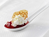 Red fruit compote with fresh goat's cheese on a china spoon