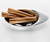 Three cinnamon sticks in a small metal dish