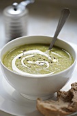 Pea soup with pesto in a soup bowl with bread