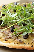 Onion, anchovy and olive pizza with rocket