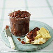 Plum chutney in a jar and on a piece of bread and cheese