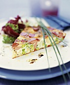 A piece of sausage and asparagus quiche with salad