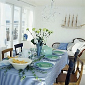 Laid table decorated with ivy and vase of flowers