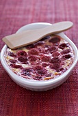Raspberry gratin in a gratin dish with wooden spatula