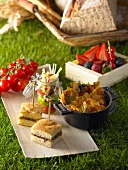Picknick mit Obst, Gemüse und Häppchen auf Gras im Freien