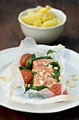 Salmon cooked in paper with garlic, almonds, spinach, tomatoes