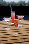 Vier verschiedene Cocktails auf einem Gartentisch