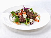 Fried lamb fillet on corn salad with tomatoes, onions, feta