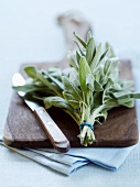 A bunch of sage and a knife on a wooden board