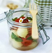 Melon salad with mint and daisies in preserving jar