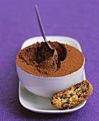 A bowl of mocha mousse with a biscuit