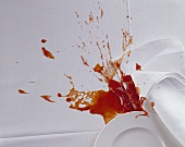Teller und Stoffserviette auf Tischtuch mit Ketchup-Fleck