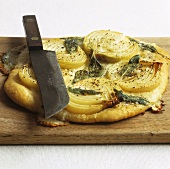 Onion and sage pizza with knife on chopping board