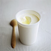 A tub of yoghurt with a wooden spoon