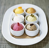 Scoops of six different ice creams in pots