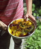 Man holding a dish of marinated peppers in his hands
