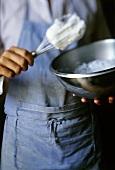 Man with a bowl of beaten egg white and whisk