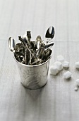 Silver spoons in a beaker