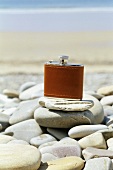 Hip flask on pebbles on beach