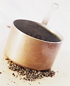 Peppercorns being crushed by a copper pan