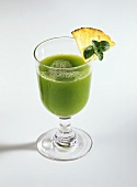 A glass of wheatgrass drink with pineapple
