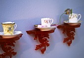 Old china cups and saucers on red plastic wall brackets