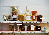 Jars of jam, jelly and relishes, bottles of liqueur on shelves